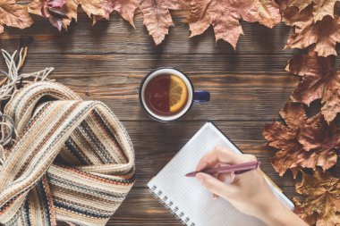 Sonbahar Not defterinizdeki notlar mevsimlik kavramı İskandinav örme eşarp moda ve sıcak siyah çay ahşap masa düz düşmüş akçaağaç yaprakları üstten görünüm vintage tarzı yatıyordu Sonbahar Kupası el yazar.