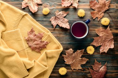 Sonbahar moda mevsimlik kavramı, sarı sıcak yumuşak rahat kazak hırka fincan sıcak siyah çay kahve düz düşmüş akçaağaç yaprakları üzerinde ahşap masa sonbahar üstten görünüm vintage tarzı yatıyordu