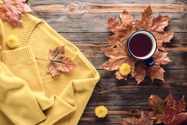 Sonbahar moda mevsimlik kavramı, sarı sıcak yumuşak rahat kazak hırka fincan sıcak siyah çay kahve düz düşmüş akçaağaç yaprakları üzerinde ahşap masa sonbahar üstten görünüm vintage tarzı yatıyordu