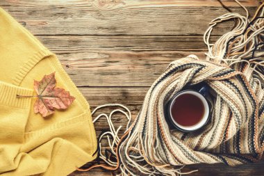 Sonbahar moda mevsimlik kavramı, sarı sıcak yumuşak rahat kazak hırka İskandinav düz düşmüş akçaağaç yaprakları üzerinde ahşap masa sonbahar üstten görünüm vintage yatıyordu eşarp fincan sıcak siyah çay kahve mamulleri