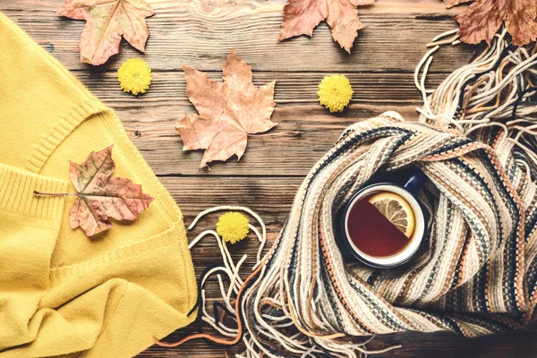 Sonbahar moda mevsimlik kavramı sarı sıcak yumuşak kazak hırka İskandinav örme eşarp düz düşmüş akçaağaç yaprakları üzerinde ahşap masa sonbahar üstten görünüm vintage tarzı yatıyordu sıcak siyah çay kahve Kupası.