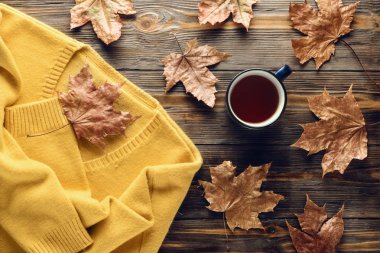 Sonbahar moda mevsimlik kavramı, sarı sıcak yumuşak rahat kazak hırka fincan sıcak siyah çay kahve düz düşmüş akçaağaç yaprakları üzerinde ahşap masa sonbahar üstten görünüm vintage tarzı yatıyordu