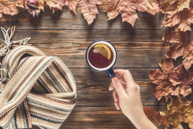Kadın el fincan sıcak siyah çay mevsimlik kavramı İskandinav örme eşarp ahşap masa düz düşmüş akçaağaç yaprakları üstten görünüm vintage tarzı yatıyordu sonbahar sonbahar moda için tutar.