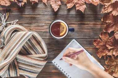 Sonbahar Not defterinizdeki notlar mevsimlik kavramı İskandinav örme eşarp moda ve sıcak siyah çay ahşap masa düz düşmüş akçaağaç yaprakları üstten görünüm vintage tarzı yatıyordu Sonbahar Kupası el yazar.