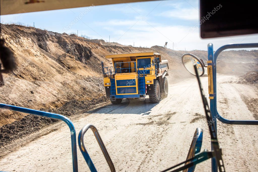 Yellow dump truck moving in a coal mine. View from another truck