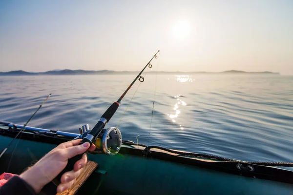 Fish-rod in fishermen's hand. Fishing  at inflatable boat