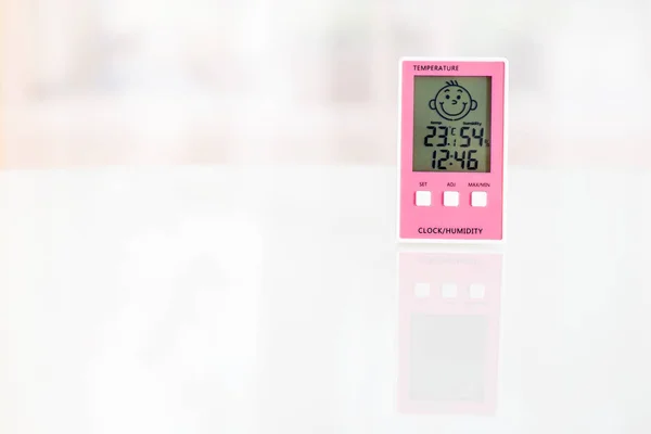 Rosa elektronisches Hygrometer auf weißem Tisch vor dem Fenster — Stockfoto