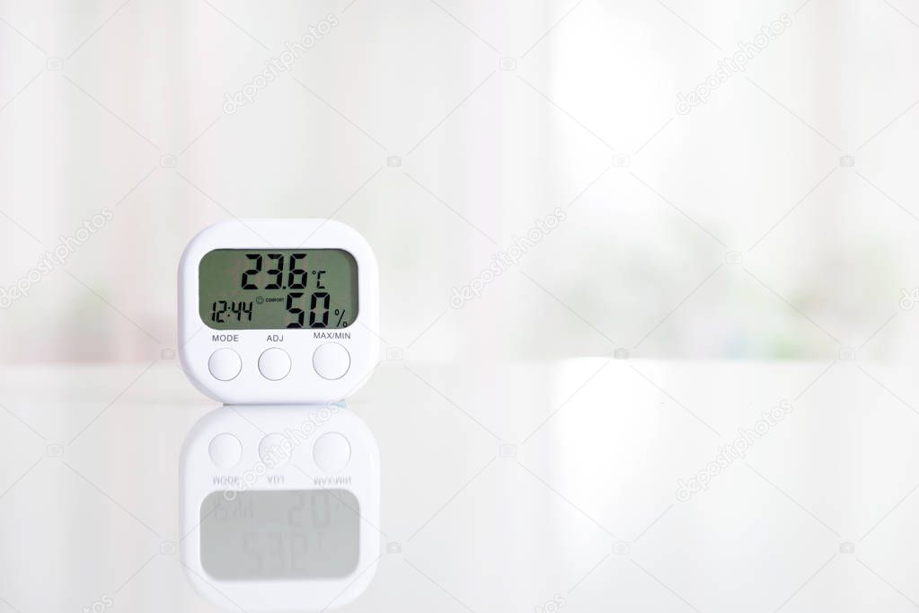 White electronic hygrometer on white table in front of the windo