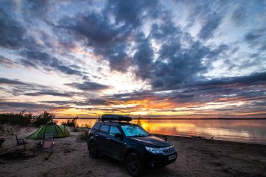 Khabarovsk, Rusya - 27 Haziran 2020: Subaru Forester gün batımında nehir kıyısında kamp yapıyor.