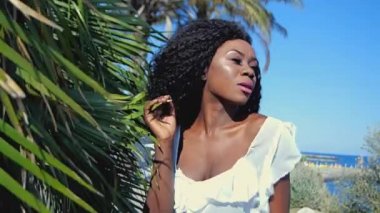 Siyah bir kızla bir palmiye ağacının yanında duruyor