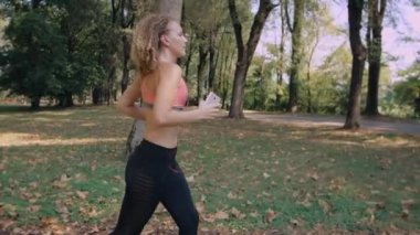 Parkta çalışan sarışın saçlı kız. Onun elinde telefon kızla. Kulaklıklar müzik kız.