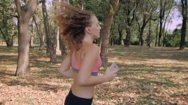 Hermosa joven modelo chica entrenamiento corre en el parque, cámara lenta — Vídeos de Stock