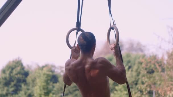 Sportler trainiert an den Ringen, er zieht hoch — Stockvideo
