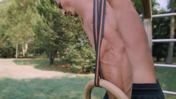 Jeune homme faisant de l'exercice sur les anneaux de gymnastique pendant l'entraînement — Video