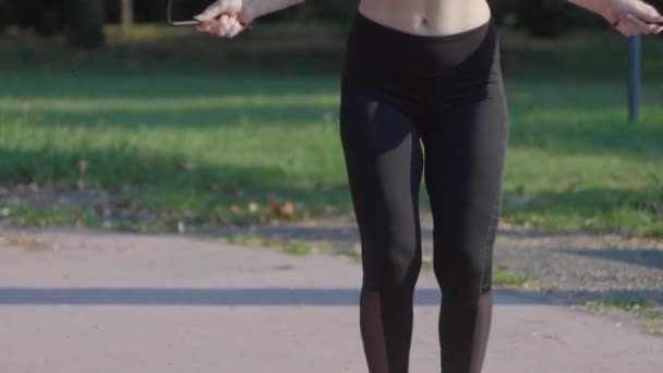 Uma mulher desportiva com uma boa figura salta corda — Vídeo de Stock
