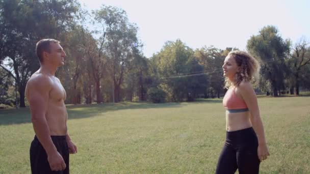 Junges Mädchen schüttet Wasser aus Sportflasche auf den Körper eines jungen Mannes — Stockvideo