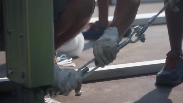 Klemmen en spankabels. Lanyard klem voor het spannen van kabel. Een werkende man trekt aan een ijzeren kabel. Concept van werk, werk professionaliteit. Stad van Como. Italië 14.05.2019 — Stockvideo