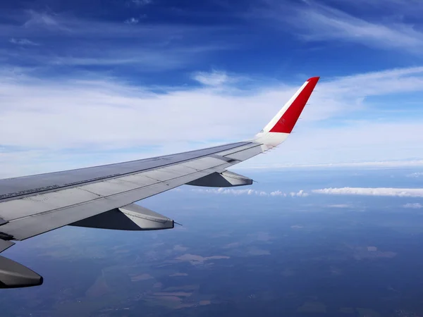 Vista attraverso oblò di velivoli sull'ala di velivoli, nuvole, cielo blu e la Terra dall'altezza di diecimila metri . — Foto Stock