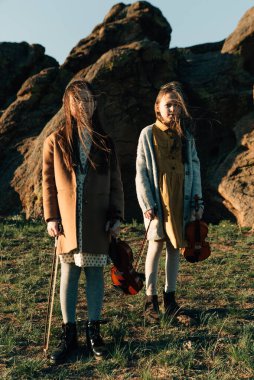 Dışarıda keman çalan iki kız kardeş gün batımında