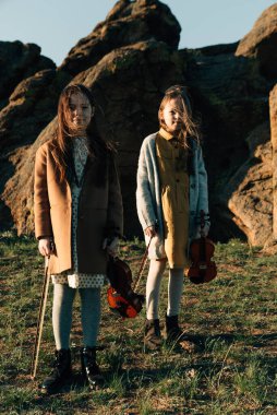 Dışarıda keman çalan iki kız kardeş gün batımında