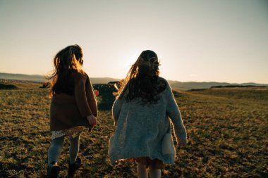 Gün batımına doğru koşan iki kız kardeş