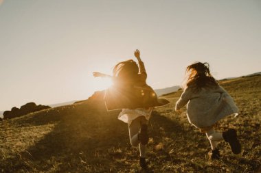 Gün batımına doğru koşan iki kız kardeş