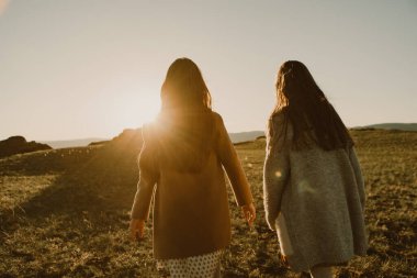 Gün batımına doğru koşan iki kız kardeş