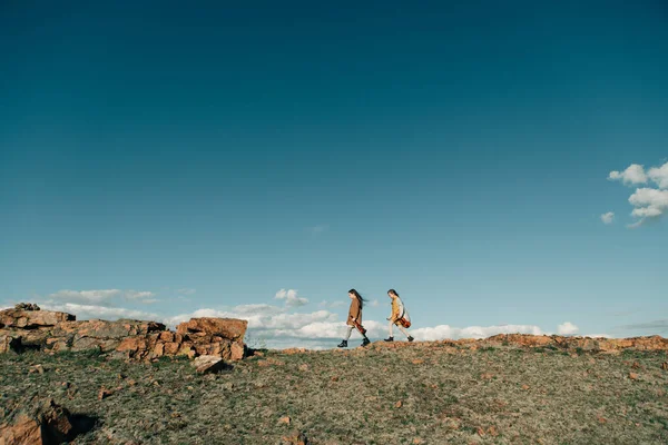 Kemanlı Iki Kız Gün Batımında Kayalık Bir Tepede Yürüyor — Stok fotoğraf