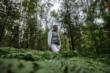 Sibirya ormanında eğreltiotu etrafında duran bir kız.