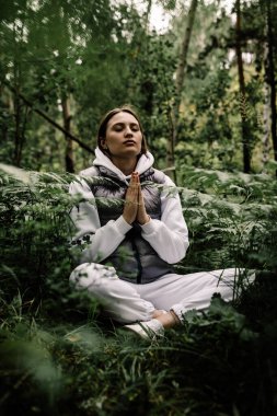 Ormanın derinliklerinde dua eden kız eğrelti otuyla el ele tutuşuyor.