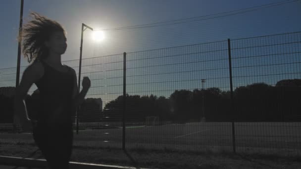 Femme utilisant le smartphone et le jogging. Silhouette jolie, femme qui court dans le parc. Vidéo en 4 K . — Video