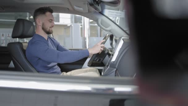 Glücklicher Fahrer, der sich an den Fingern zeigt und im Auto sitzt. — Stockvideo