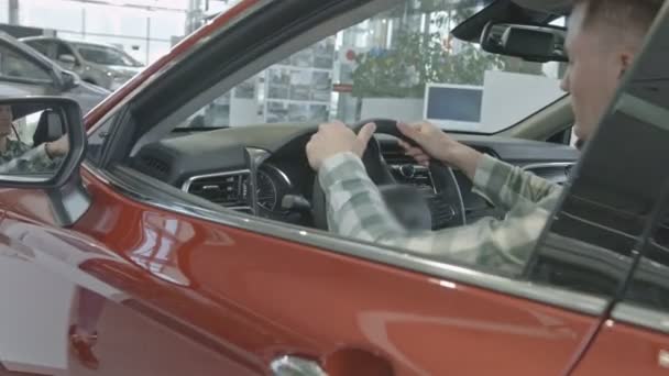 Człowiek siedzi w nowo kupiony samochód, głaszcząc kierownicy. — Wideo stockowe