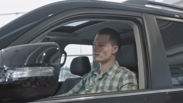 Vista do lado do homem sentado em carro novo no salão de beleza — Vídeo de Stock