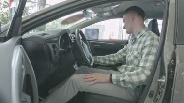 Adam şoför koltuğunda oturur. İç lambayı mutlu kendine güvenen delikanlı salon araba inceliyor. 4k video.