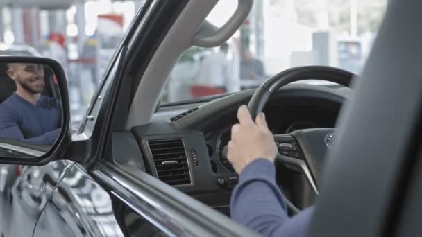 Homme appréciant l'intérieur de la voiture dans l'automobile neuve dans le salon automobile — Video
