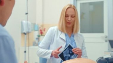 Kocası olan hamile bir kadın onun bebek ultrason görünüyor. Mutlu bir çift doktor gülümsüyor
