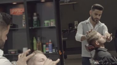 Profesyonel kuaför berber dükkanı sandalyede oturan genç erkek istemci iş parçacığı yordamı ve kaşları düzeltme şeklinde yapmak beyaz gömlekli. Stil oluşturma ve bakımı kavramı.