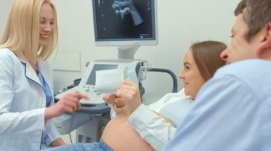 Bir kadın doktoru, hamile bir kadına ultrason taraması yapıyor. Kız yeni doğmuş bir kadın bekliyordu. Annelik anlayışı.