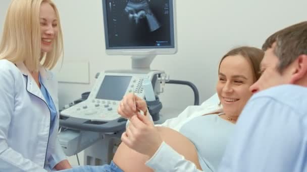 Een arts van een vrouw geeft een foto van echografie te scannen naar een zwangere vrouw. Het meisje verwachtte een pasgeborene. Conceptie van het moederschap. — Stockvideo