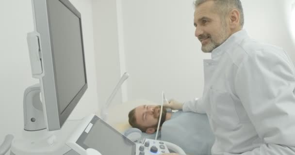 Primer plano del paciente hombre acostado en el consultorio médico. Mano del médico en guante médico blanco con sonda de ultrasonido, examinando el cuello y los ganglios linfáticos . — Vídeo de stock