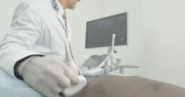 Karın muayenesinde çıplak gövdesinde yatan Afrikalı adamın yan görünümü. Doktor özel profesyonel cihaz tutan beyaz tıbbi eldiven giyiyor.