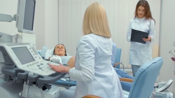 Hamile kadın ve kocası ultrason taramasına bakıyor. Kocası elinde karısını tutuyor — Stok video