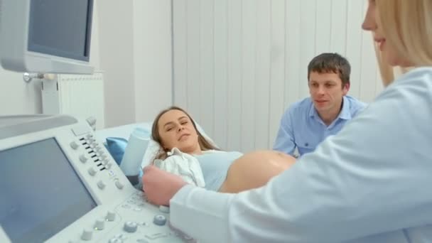Kobieta w ciąży i jej mąż patrząc na USG dziecka. Mąż trzyma żonę za rękę — Wideo stockowe