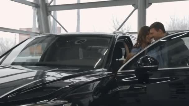 Муж и жена с сыном и дочерью выбирают новую машину в автоцентре — стоковое видео