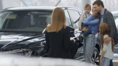 Araba satıcısı olarak çalışan genç ve güzel bir kadın. Elinde bir belge olan siyah bir dosya var. Bir adam kontrat imzalıyor, araba alıyor. Yeni arabasının yanında mutlu bir aile satın alındı.