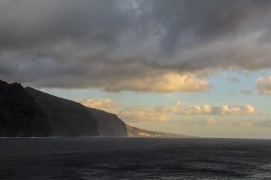 Okyanus kıyısı. Dağlardaki körfez, güneşle aydınlanıyor.