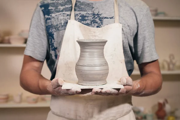 Giovanotto con in mano un vaso di argilla. Creare ceramiche. Artigiano con ce — Foto Stock