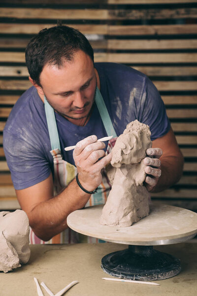 Man shaping sculpture in the studio.