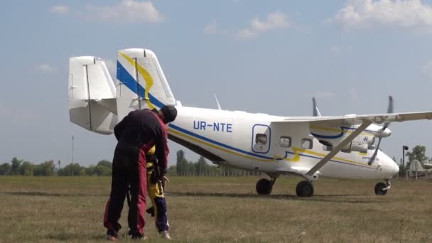 乌克兰 2018年8月26日降落在机场后的快乐伞兵 男教练帮助伞兵解开带子 飞机沿着他们旁边的机场旅行 — 图库视频影像